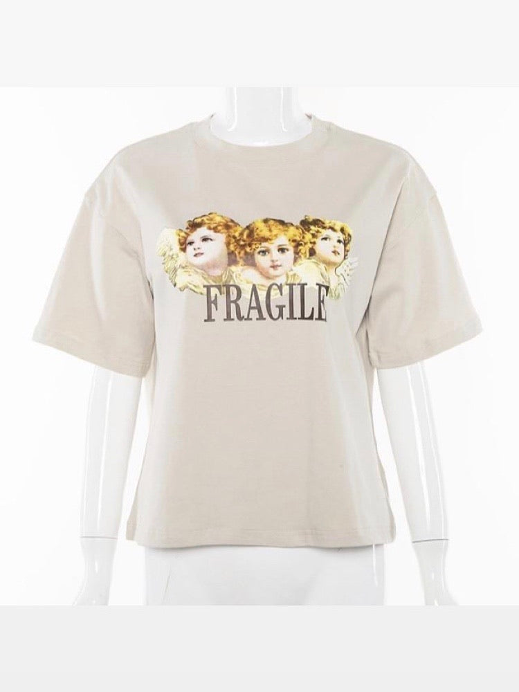 front view of our beige tshirt with three angels printed on the front with the text below fragile in brown