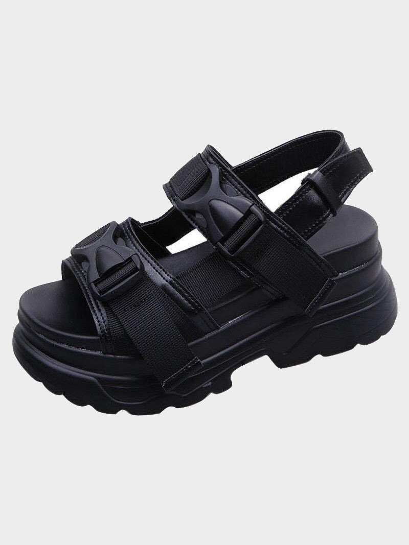 black faux leather sandal with small platform sole, streetwear style with two elastic strap with plastic buckle covering two straps that goes above the foot