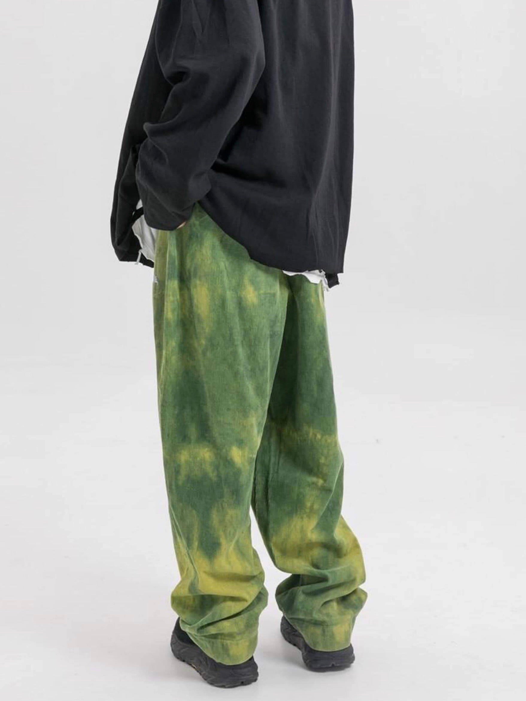 back view of our green tie and dye velvet long pants vh studios with made extreme embroidered in white on the top of the left thigh. t has an elastic waist adjustable with a white lace