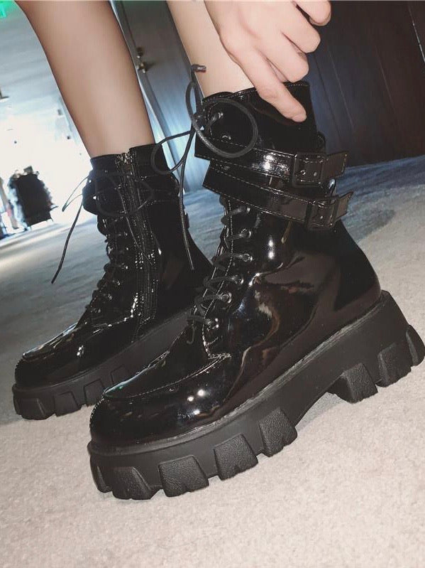 black shiny faux leather punk boot with small platform sole with two buckle strap at the top on a model