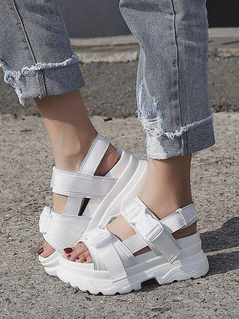 white faux leather sandal with small platform sole, streetwear style with two elastic strap with plastic buckle covering two straps that goes above the foot