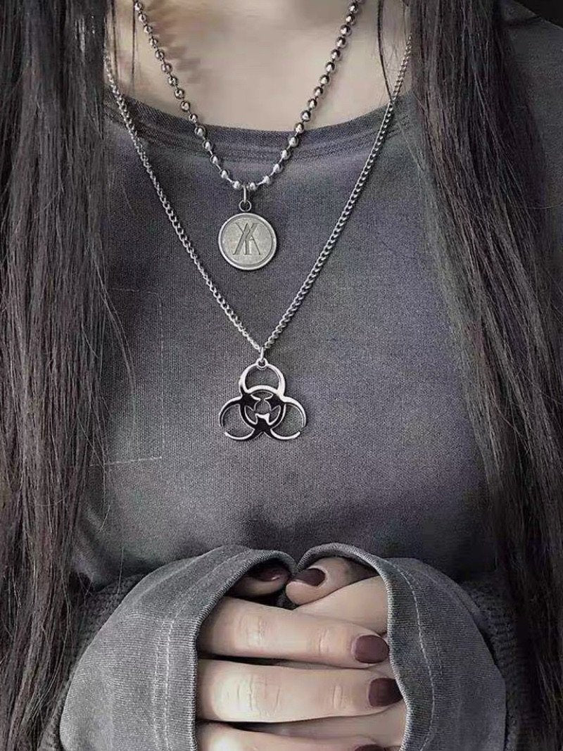 silver biohazard logo chain worn by a woman