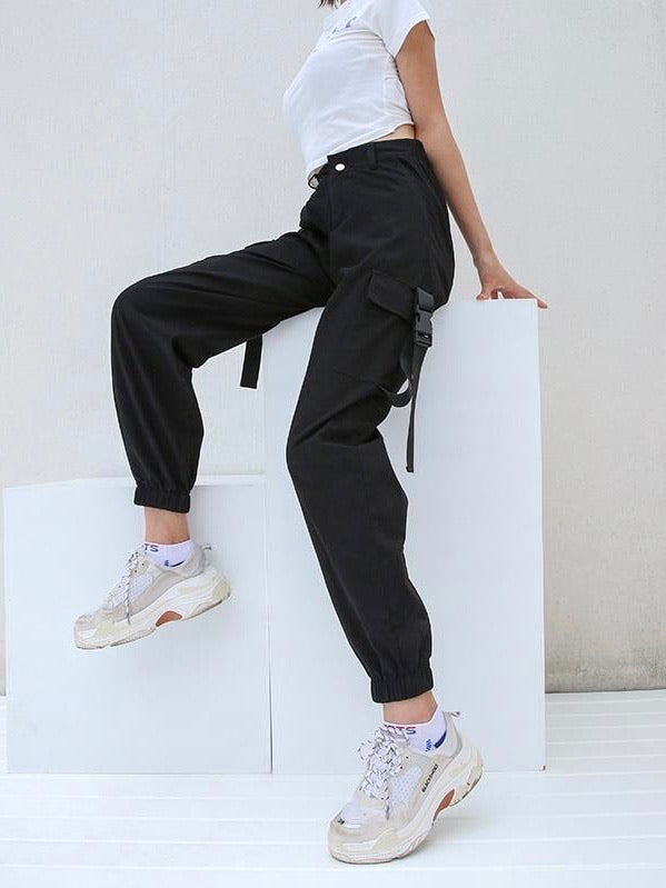 side view of the black high waist cargo pants with two big side pockets closed by a plastic buckle strap