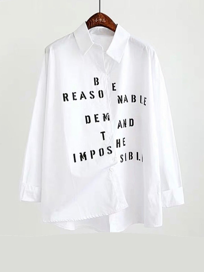 white shirt with a black texte printe split by the buttons that close the shirt saying be reasonable demand the imposible