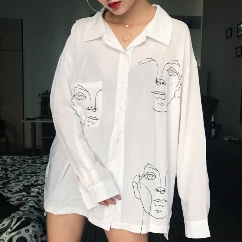 white blouse with three black drawn sketches of faces worn by a woman